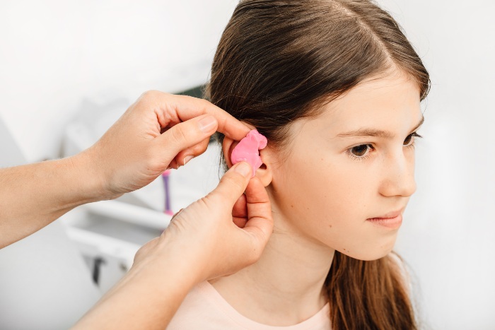 Audiologist fitting custom pink hearing protection earmold in Colorado Springs, CO